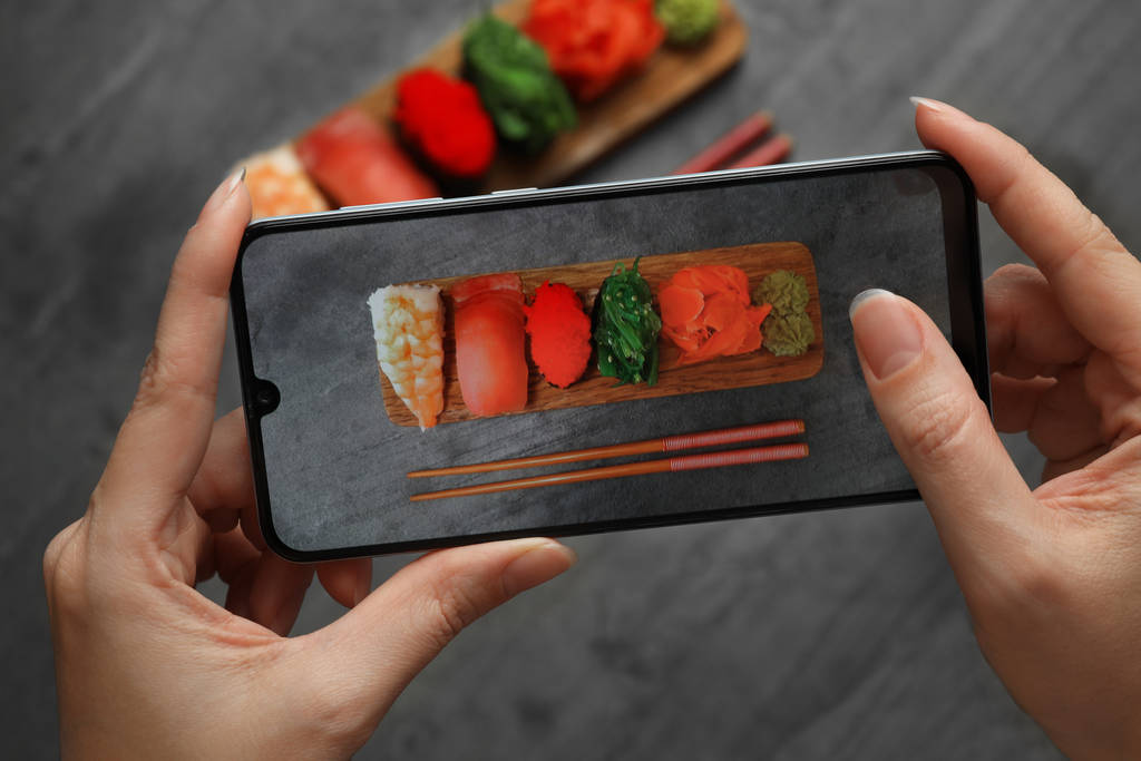 Блогер фотографирует суши за серым столом, крупным планом
 - Фото, изображение