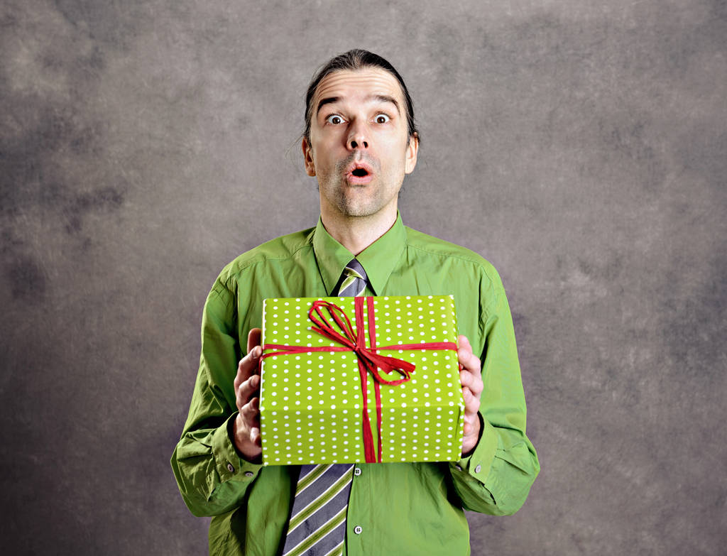 jovem homem em camisa verde e gravata com caixa de presente verde é surpreendido
 - Foto, Imagem