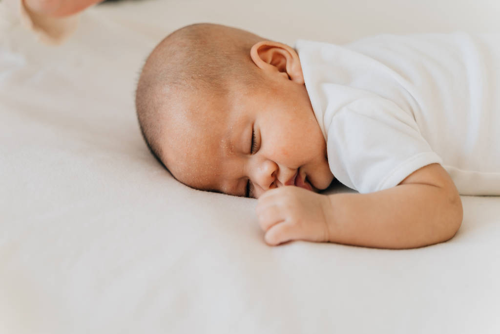 Un nouveau-né qui dort sur son ventre au lit à la maison. Asiatique enfant bas vers le haut position de sommeil
 - Photo, image