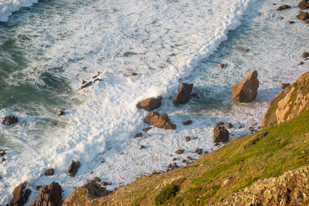 Dalgalar, uçurumlar ve kayalar Portekiz Cabo da Roca 'da batan güneş ışınlarında. - Fotoğraf, Görsel