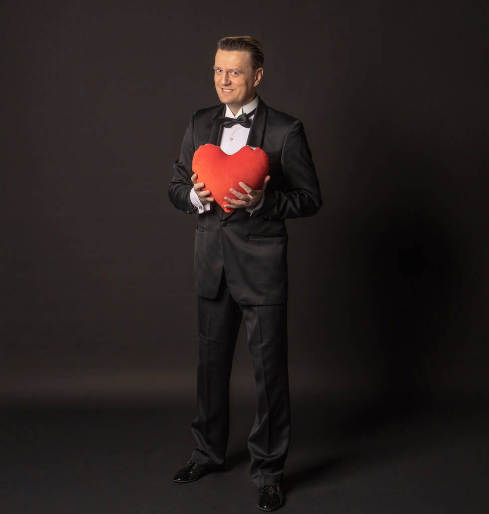 El caballero de San Valentín con el amor en el corazón en la chaqueta, el fondo negro
.  - Foto, Imagen