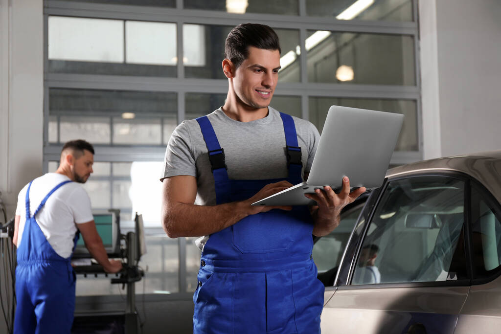 Mechanic with laptop doing car diagnostic at automobile repair  - Photo, Image