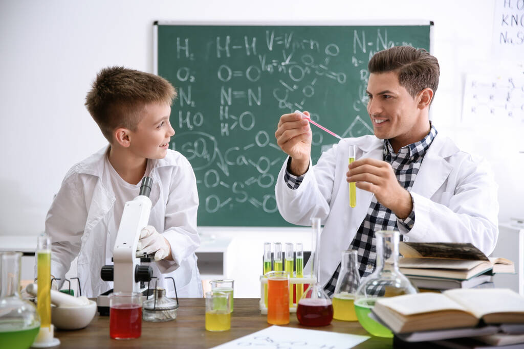 Profesor con alumno haciendo experimento en la mesa en clase de química
 - Foto, Imagen