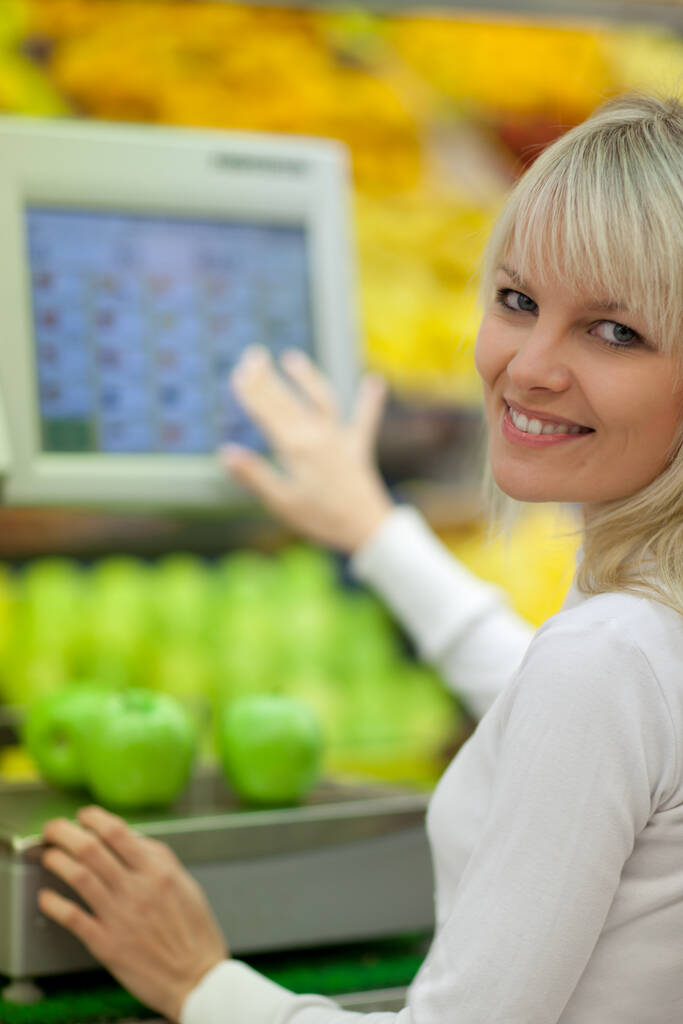 Kaunis nuori nainen ostamassa hedelmiä ja vihanneksia päivittäistavarakaupan / supermarketin tuoteosastolla
 - Valokuva, kuva