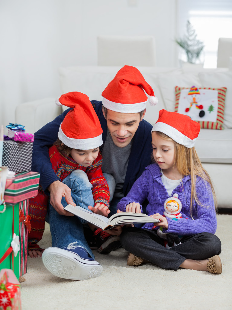 vader en kinderen in santa hoeden lezen van boek - Foto, afbeelding