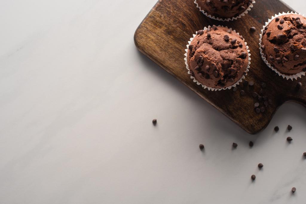 vue du dessus des muffins au chocolat frais sur la planche à découper en bois sur la surface du marbre
 - Photo, image