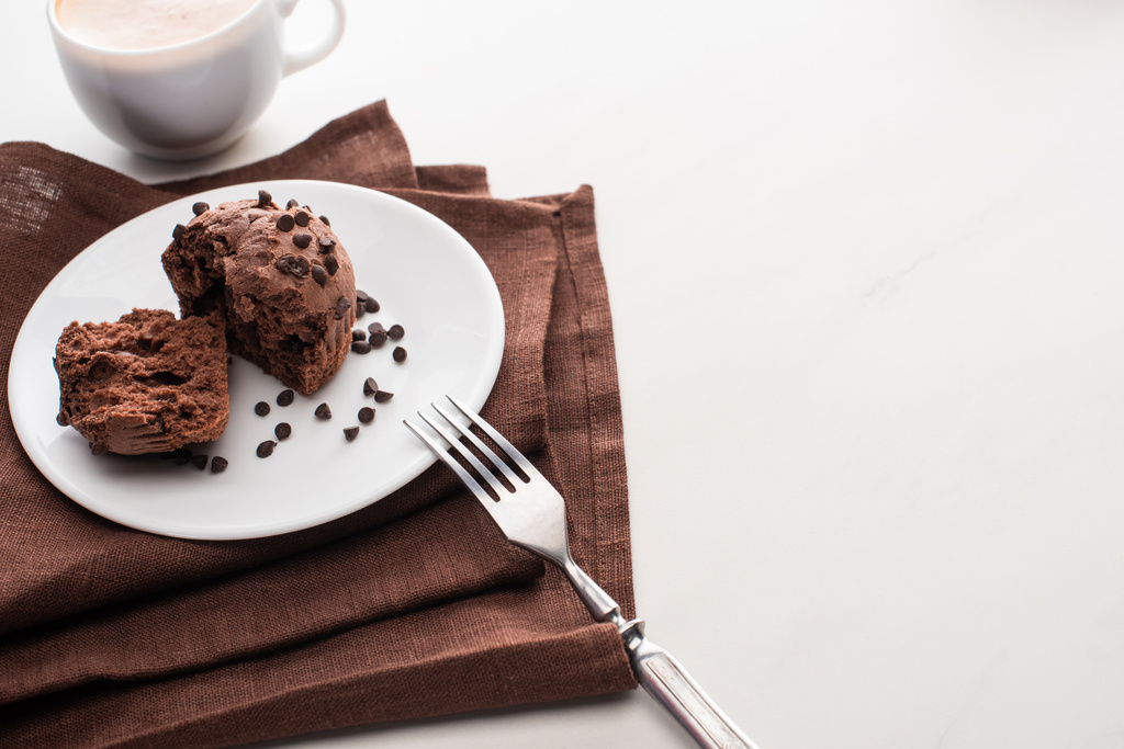 świeże czekoladowe babeczki na talerzu z widelcem na brązowej serwetce przy kawie - Zdjęcie, obraz