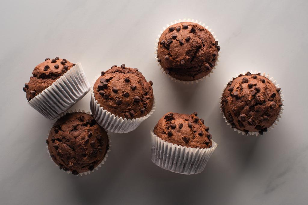 top view of fresh chocolate muffins on marble surface - Fotoğraf, Görsel