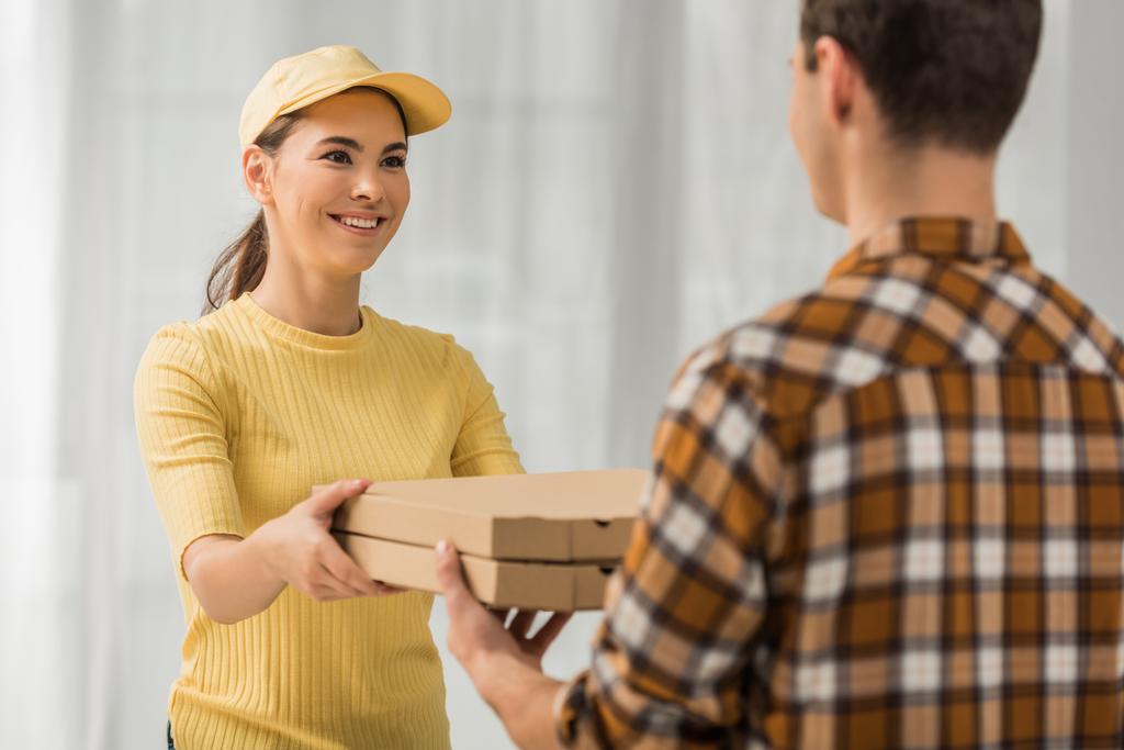 Valikoiva painopiste hymyilevä kuriiri antaa pizza laatikot ihmiselle
  - Valokuva, kuva