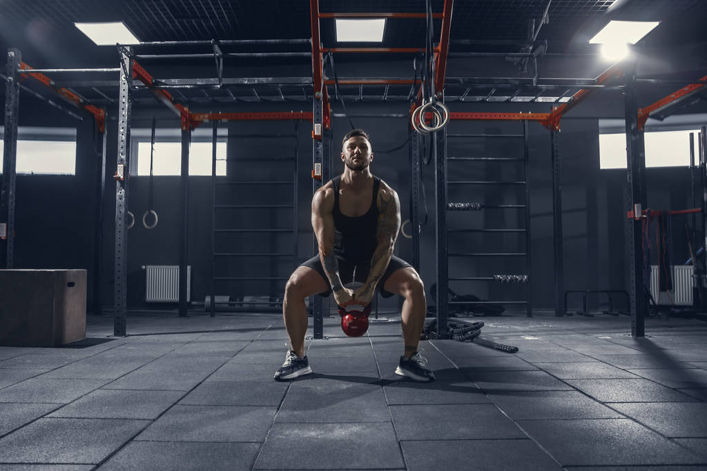 Męski atleta trenujący ciężko na siłowni. Koncepcja sprawności i zdrowego życia. - Zdjęcie, obraz