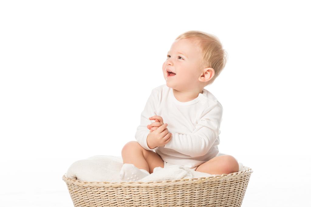 Aranyos gyerek néz fel és nevet, ül a takaró kosárban fehér háttér - Fotó, kép