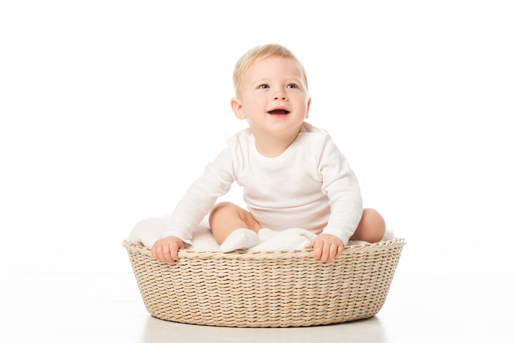 Cute boy with open mouth holding basket while sitting inside on white background - Photo, Image