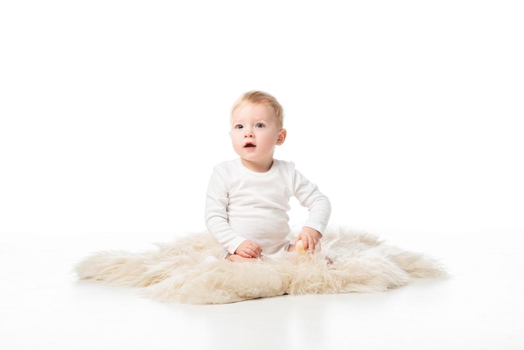 Enfant mignon avec bouche ouverte assis sur la fourrure sur fond blanc
 - Photo, image