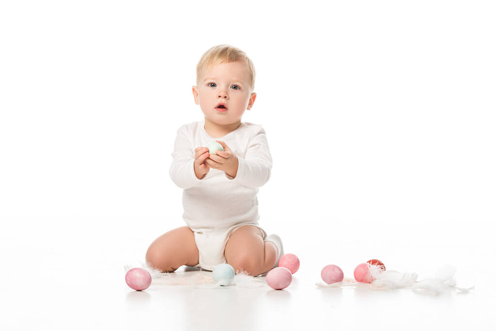Enfant à bouche ouverte, tenant un œuf de Pâques et regardant la caméra sur fond blanc
 - Photo, image
