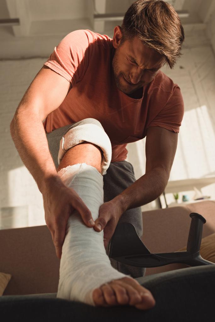 Low angle view of man with broken leg having pain at home - Photo, Image