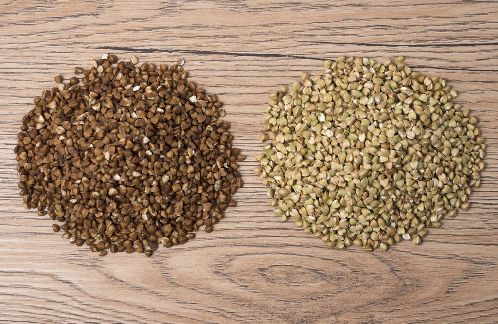 Pile of buckwheat and green buckwheat on wooden background. Top view. - Photo, Image