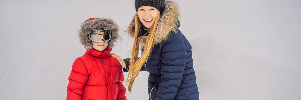 Мама надевает лыжные очки для своего сына БАННЕРА, ДЛЯ ФОРМАТА
 - Фото, изображение