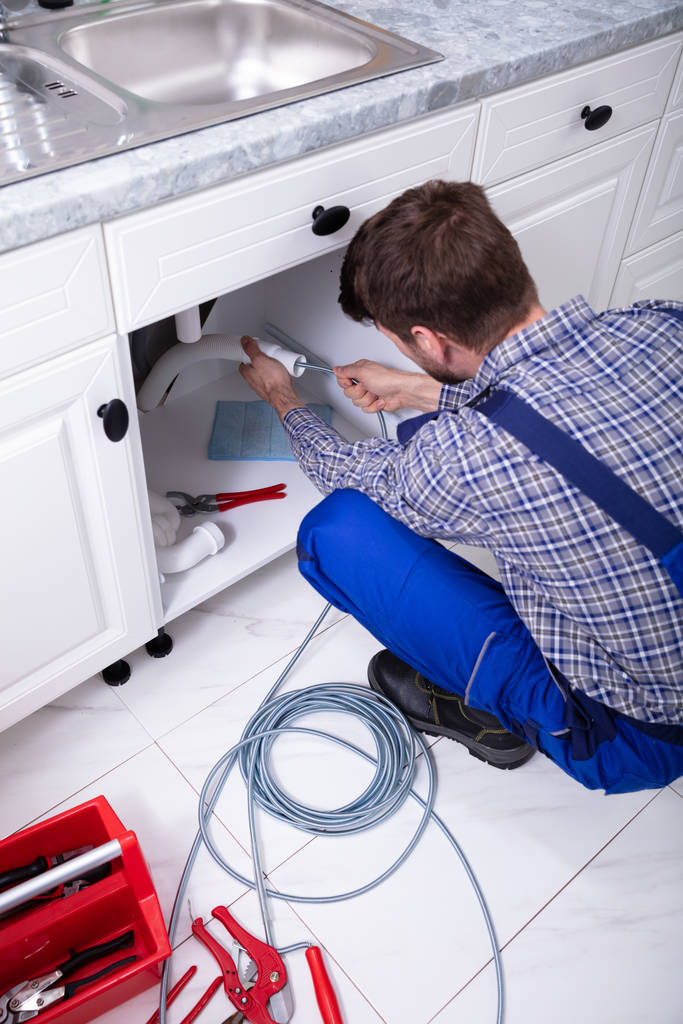 junger männlicher Installateur reinigt verstopftes Spülrohr in Küche - Foto, Bild