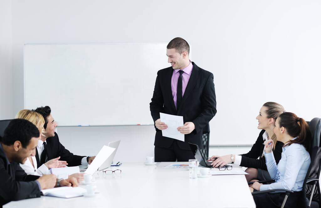 Группа молодых бизнесменов, сидящих в зале заседаний во время встречи и обсуждения с бумажной работой - Фото, изображение