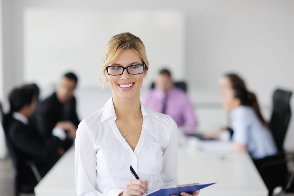Erfolgreiche Geschäftsfrau steht mit ihren Mitarbeitern im Hintergrund im modernen, hellen Büro - Foto, Bild