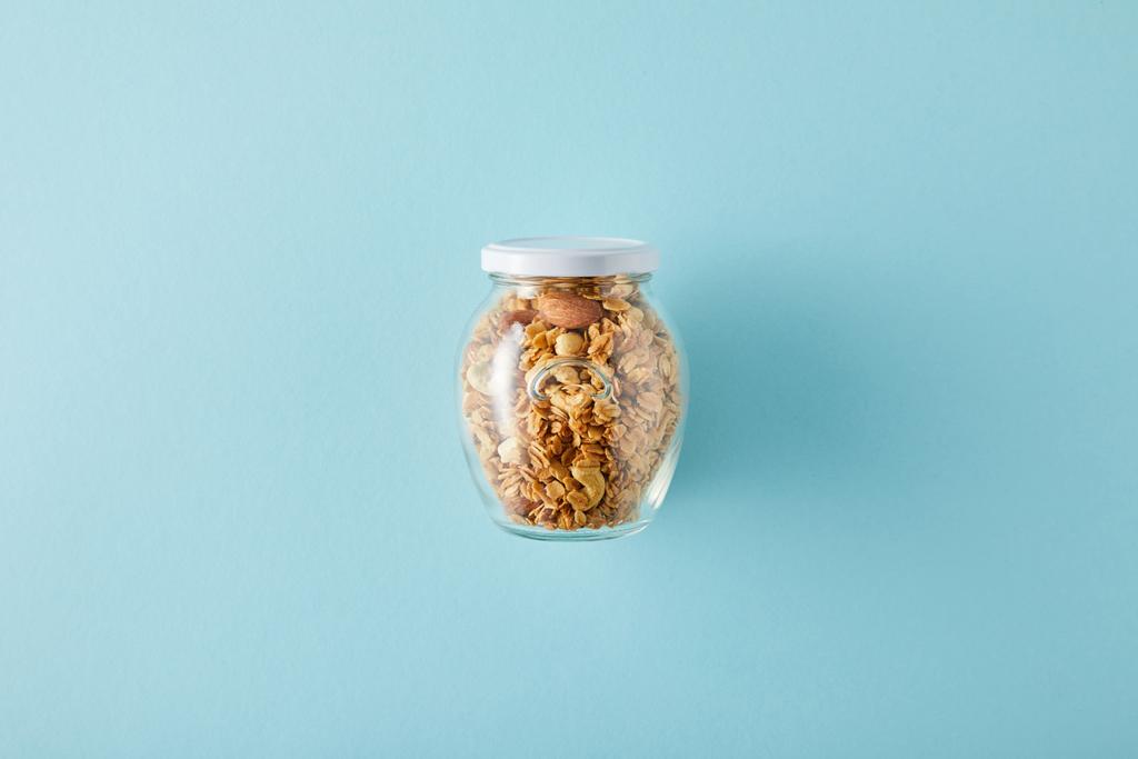 Mavi arkaplanda granola kavanozunun üst görünümü - Fotoğraf, Görsel