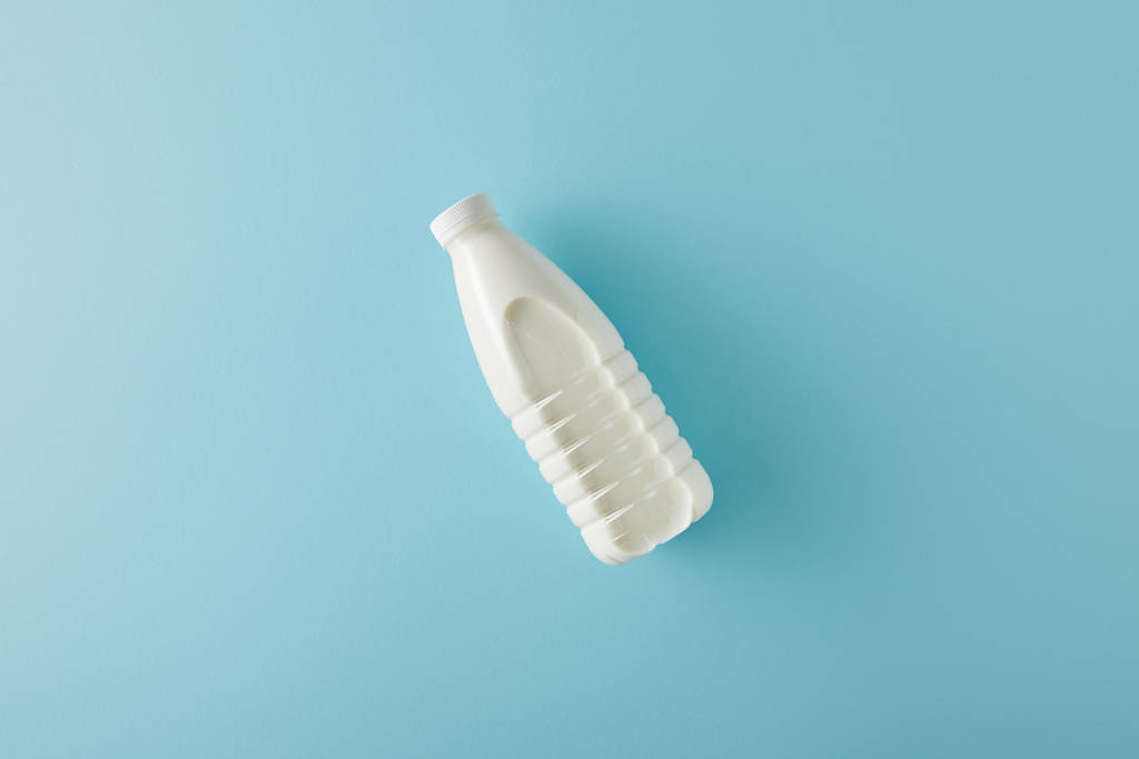 Вид зверху пляшки молока на синьому фоні
 - Фото, зображення