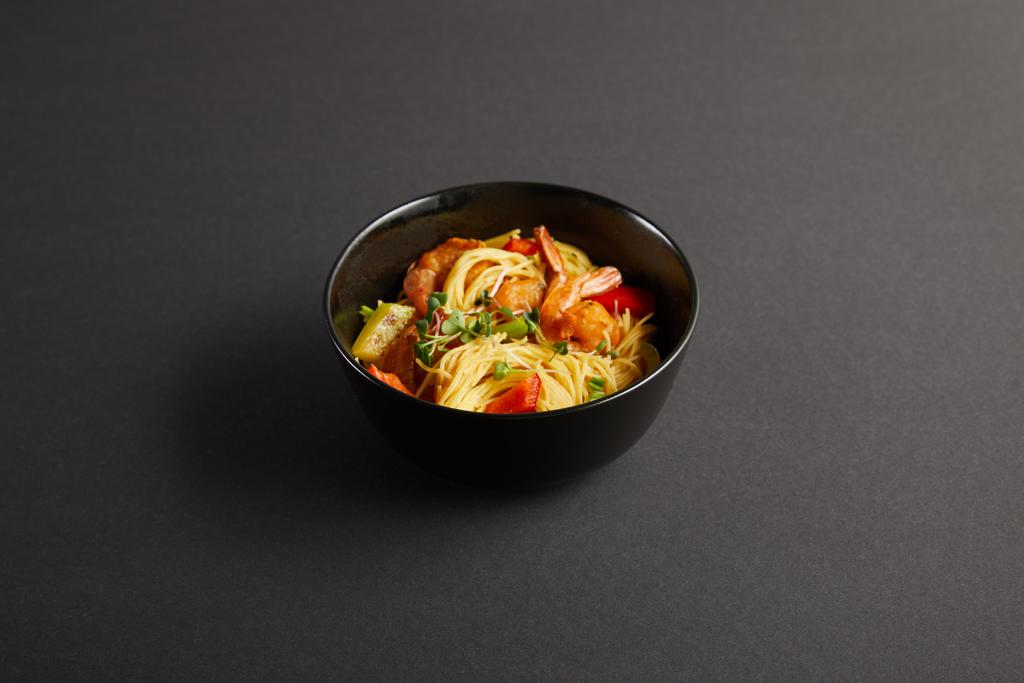 noodles με γαρίδες και λαχανικά σε μπολ σε μαύρο φόντο - Φωτογραφία, εικόνα
