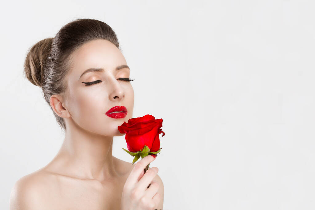 Kobieta z czerwoną różą z zamkniętymi oczami. Odizolowane na biało - Zdjęcie, obraz