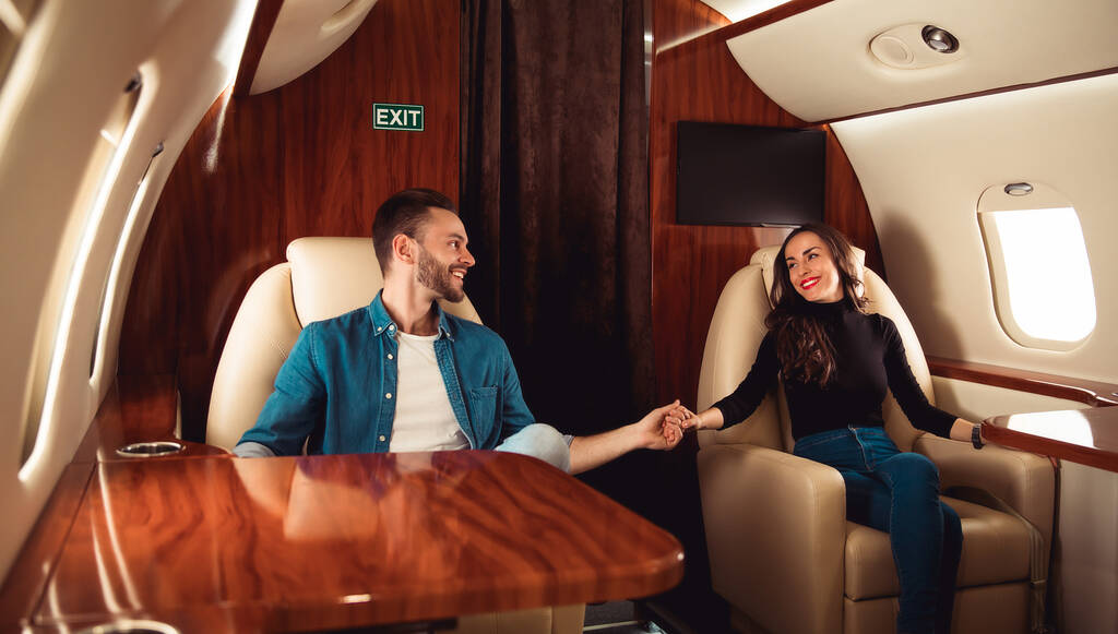 ερωτευμένο ζευγάρι στο αεροπλάνο που κρατιέται χέρι χέρι - Φωτογραφία, εικόνα