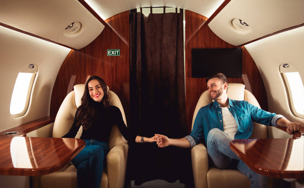 ερωτευμένο ζευγάρι στο αεροπλάνο που κρατιέται χέρι χέρι - Φωτογραφία, εικόνα