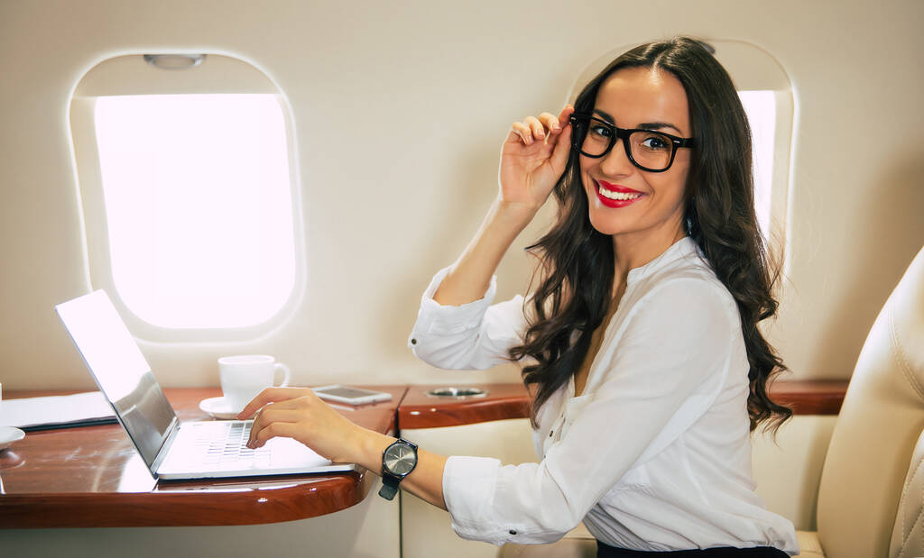 Jonge vrouw in het vliegtuig met laptop  - Foto, afbeelding