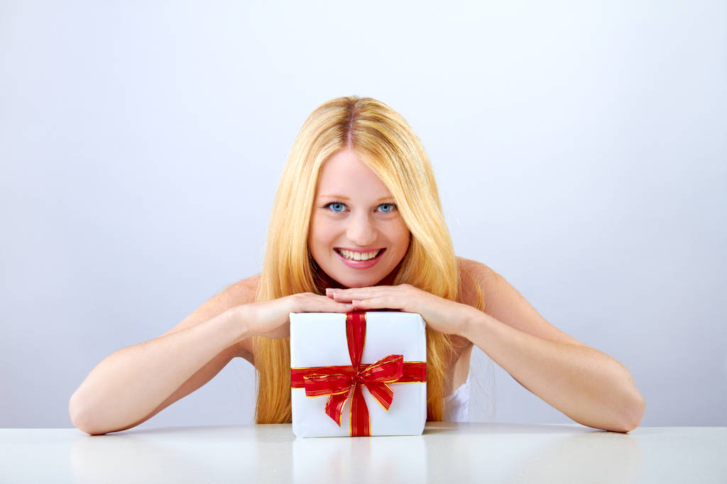 όμορφη ξανθιά γυναίκα κρατώντας ένα χριστουγεννιάτικο δώρο χαμογελά - Φωτογραφία, εικόνα