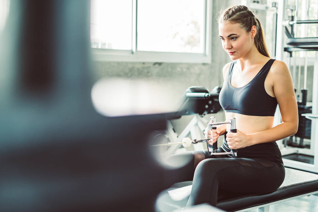 Fitness woman in training showing exercises with exercise-machine in gym, fitness concept, sport concept. Young sporty woman stretching at gym. Change for health concept. - Photo, Image