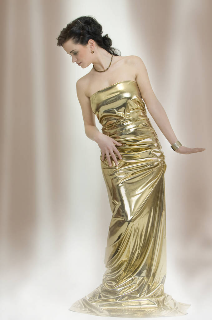 fiatal elegáns karcsú nő, mint egy szobor arany ruhában - Fotó, kép