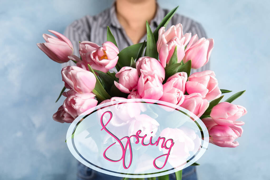 Vrouw met mooie roze lente tulpen op lichtblauwe achtergrond - Foto, afbeelding