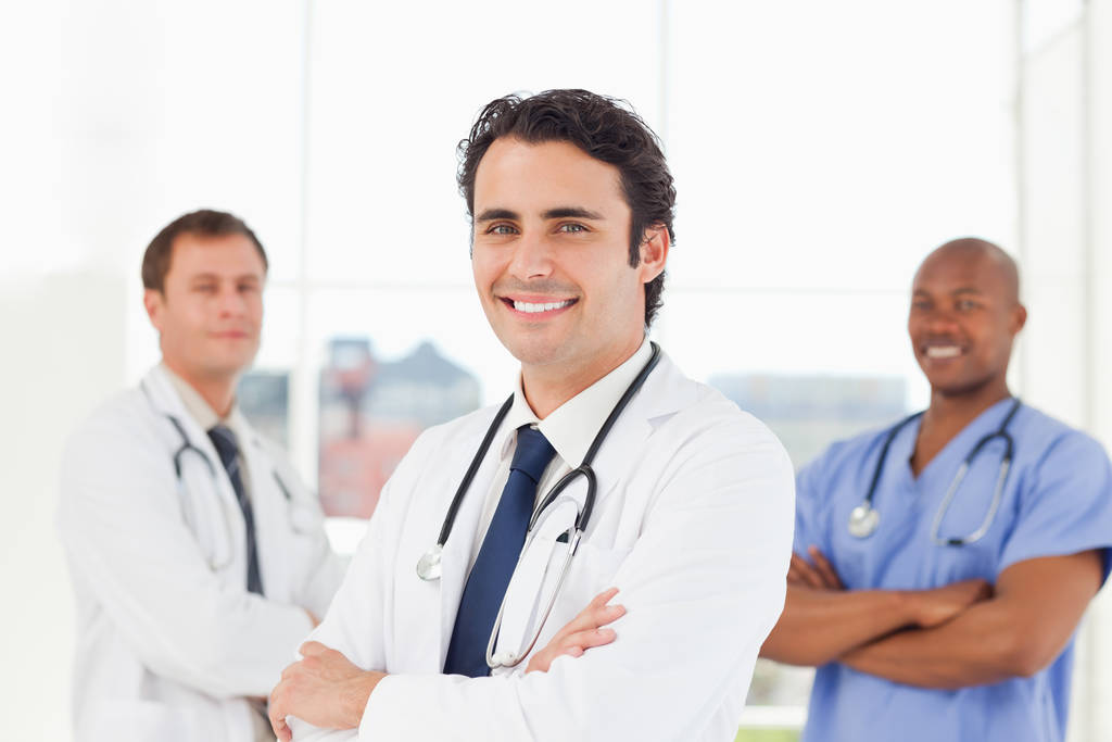 Smiling male doctors with their arms crossed standing in front of a window - Photo, Image