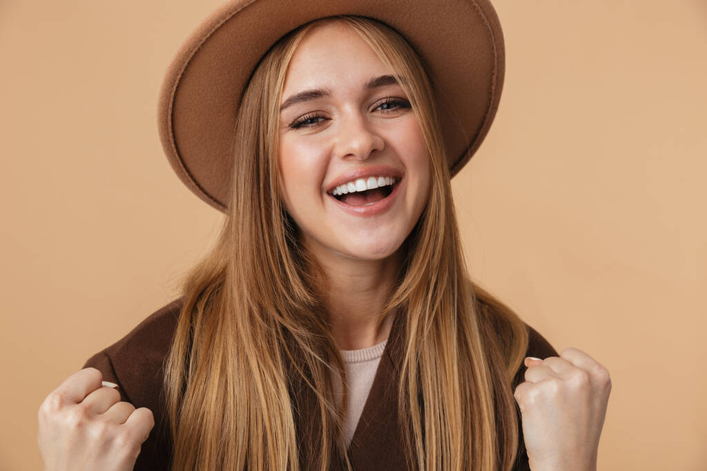 Obraz młodej dziewczyny w kapeluszu uśmiechniętej i zaciskającej pięści  - Zdjęcie, obraz