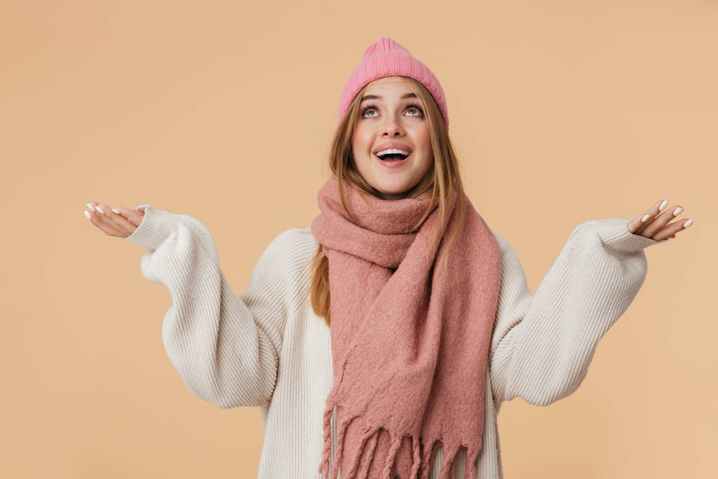 Image of girl wearing winter hat looking upward with arms wide o - Photo, Image