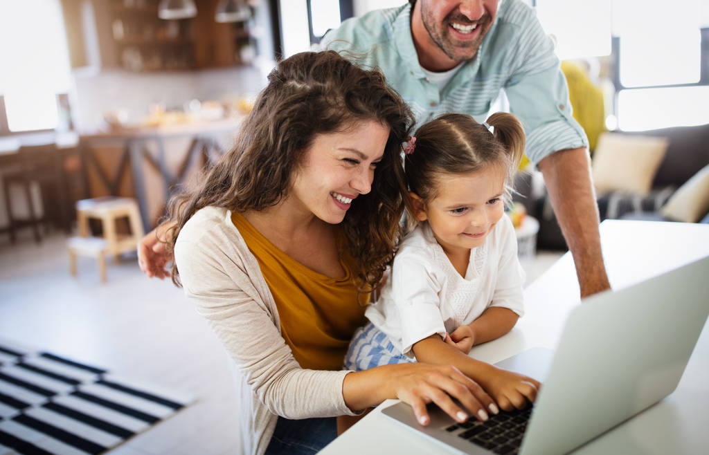 Щаслива молода сім'я проводить час вдома і використовує ноутбук
 - Фото, зображення