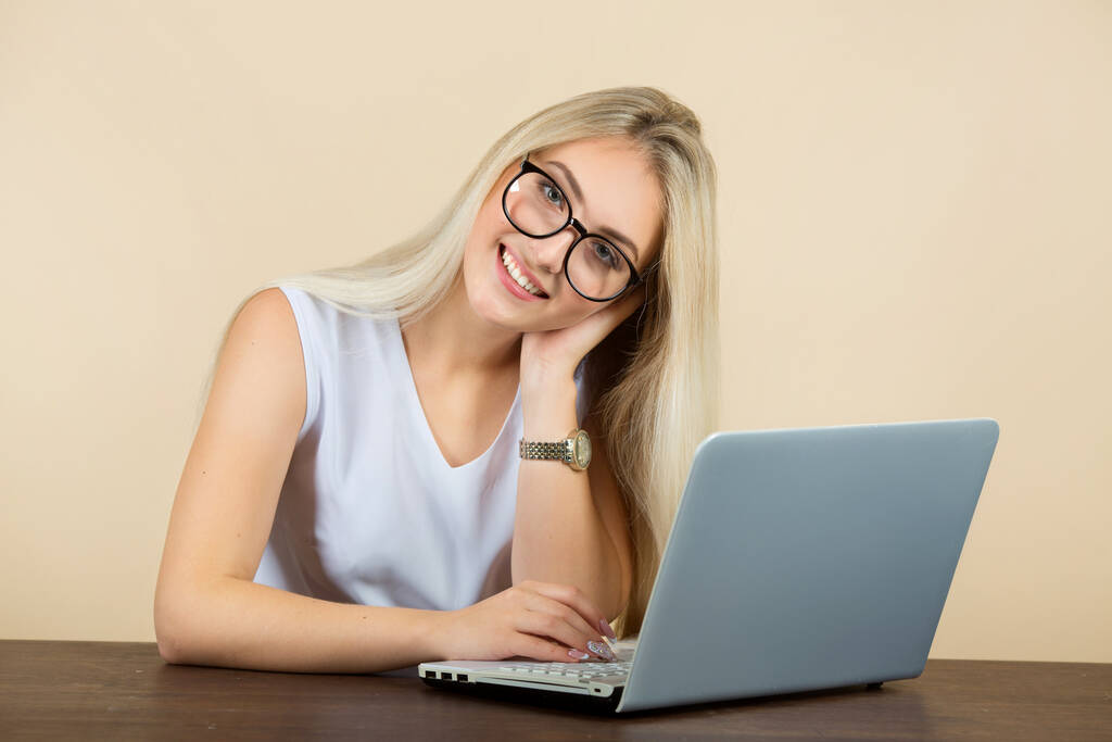 piękna młoda kobieta w okularach na beżowym tle z laptopem - Zdjęcie, obraz