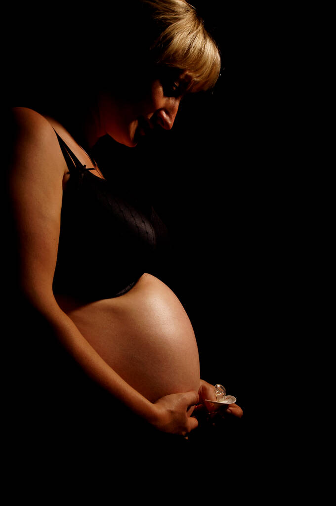 mujer embarazada con vientre desnudo y chupete
 - Foto, Imagen