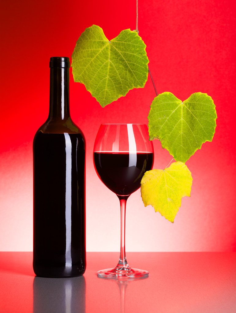 butelkę i kieliszek czerwonego wina z winogron pozostawia - Zdjęcie, obraz
