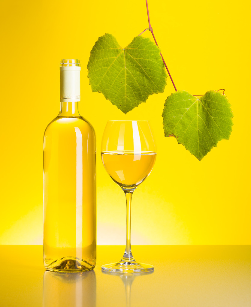 palack és a pohár fehér bor, szőlő levelek - Fotó, kép