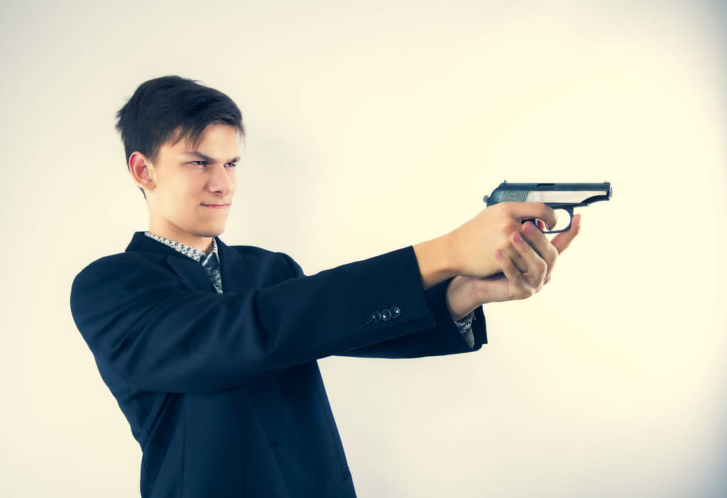 Профільний вигляд молодого чоловіка в діловому одязі, який тримає пістолет перед собою. Ізольовано на cthjv, пробіл для копіювання
 - Фото, зображення
