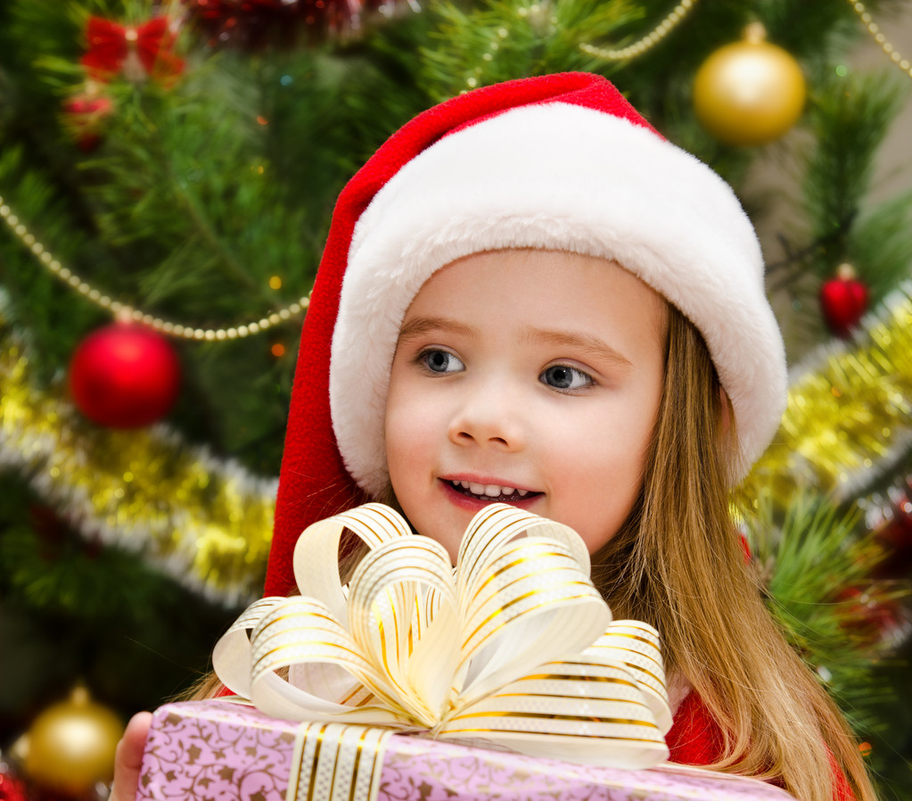 schattig klein meisje in kerstmuts met heden - Foto, afbeelding