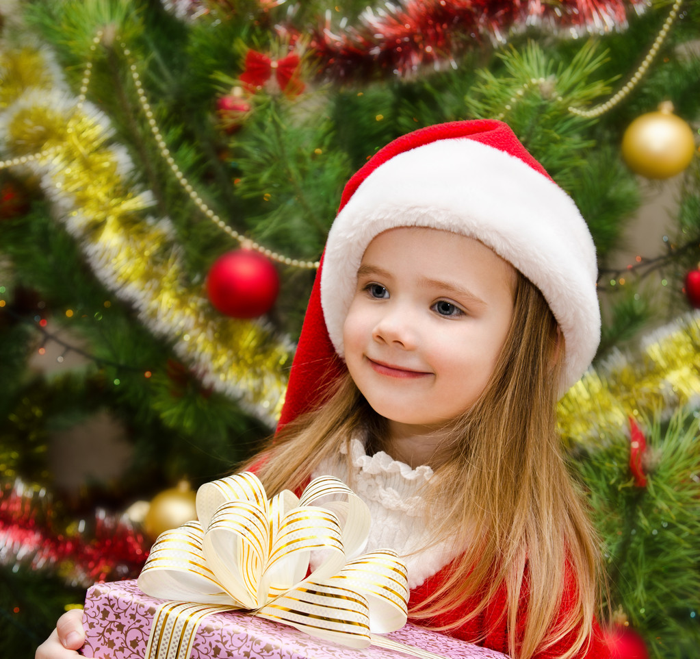 Carino bambina in cappello di Babbo Natale con regalo
 - Foto, immagini