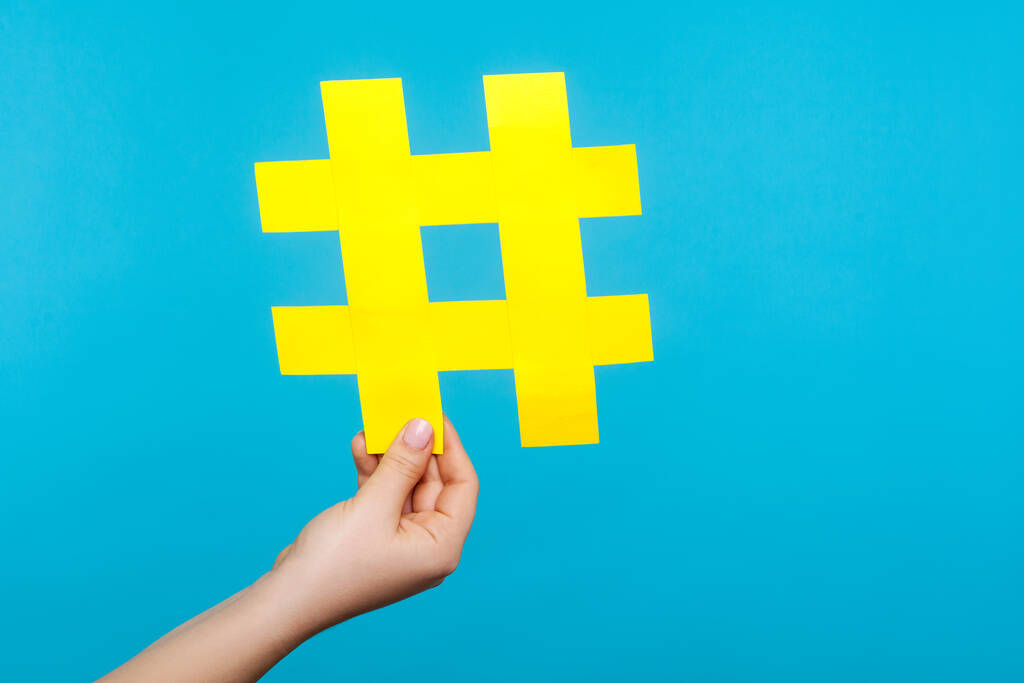 Gros plan de la main féminine tenant un grand signe de hashtag en papier jaune, ha
 - Photo, image