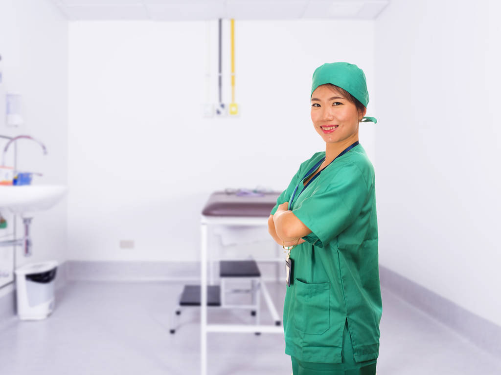 joven hermosa y feliz médico de medicina asiática o enfermera de hospital en uniformes verdes y sombrero de cirujano sonriendo confiado en el concepto de atención médica
 - Foto, Imagen