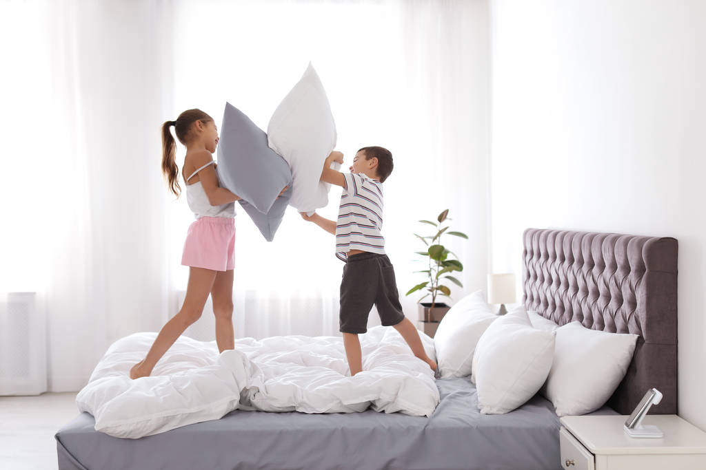 Enfants heureux ayant une bataille d'oreillers dans la chambre
 - Photo, image