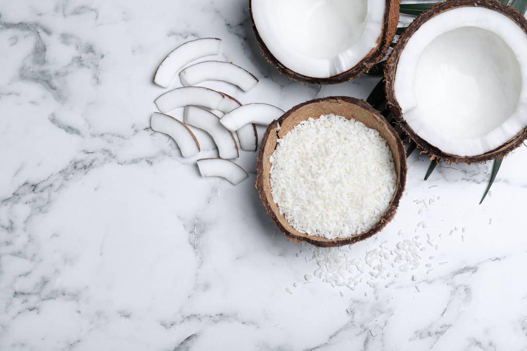 Flat lay composition with fresh coconut flakes on white marble table. Space for text - Fotoğraf, Görsel